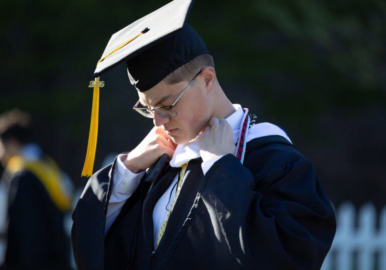 A University of Rochester graduate adjusts his academic hood before the Commencement Weekend ceremony.