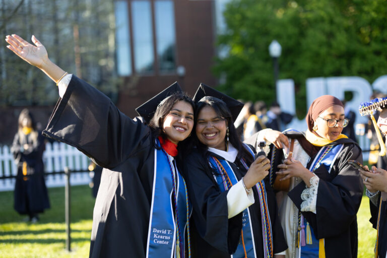University of Rochester graduates smile together while taking photos before the Commencement Weekend ceremony.
