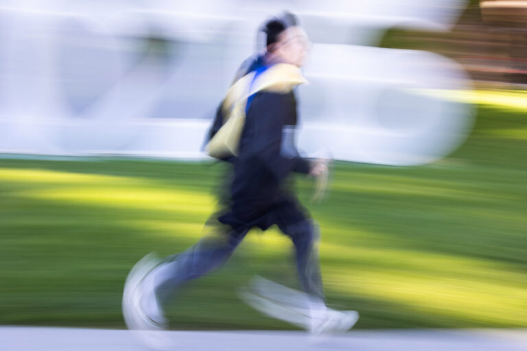 A University of Rochester graduate runs across the grass in a motion-blurred photo during Commencement Weekend.