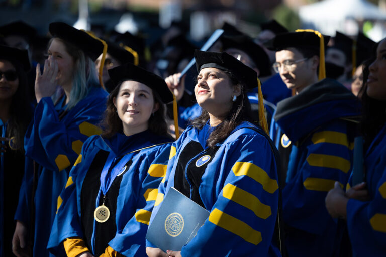 University of Rochester graduates in blue doctoral regalia look toward the stage during Commencement Weekend.