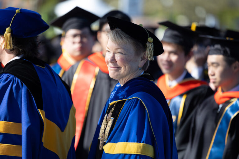 A University of Rochester faculty member smiles in academic regalia during Commencement Weekend.