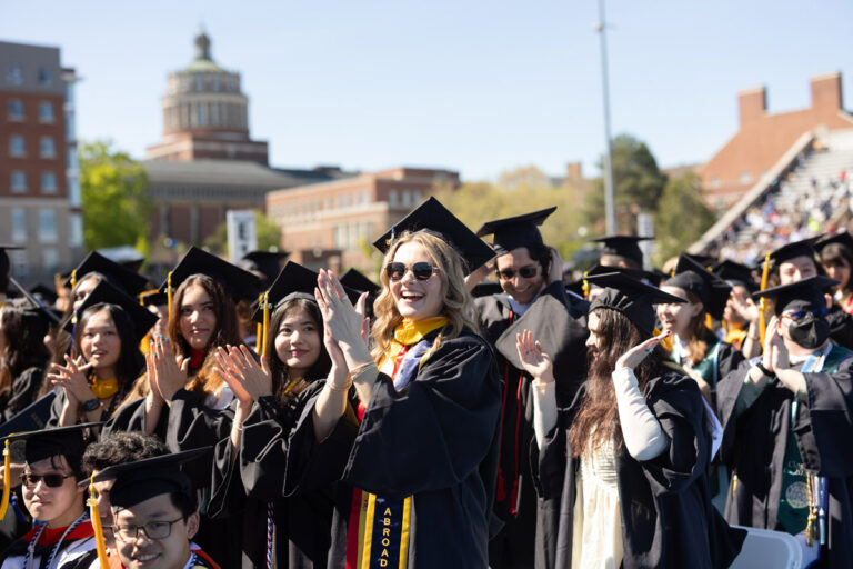 University of Rochester graduates in caps and gowns applaud during Commencement Weekend.