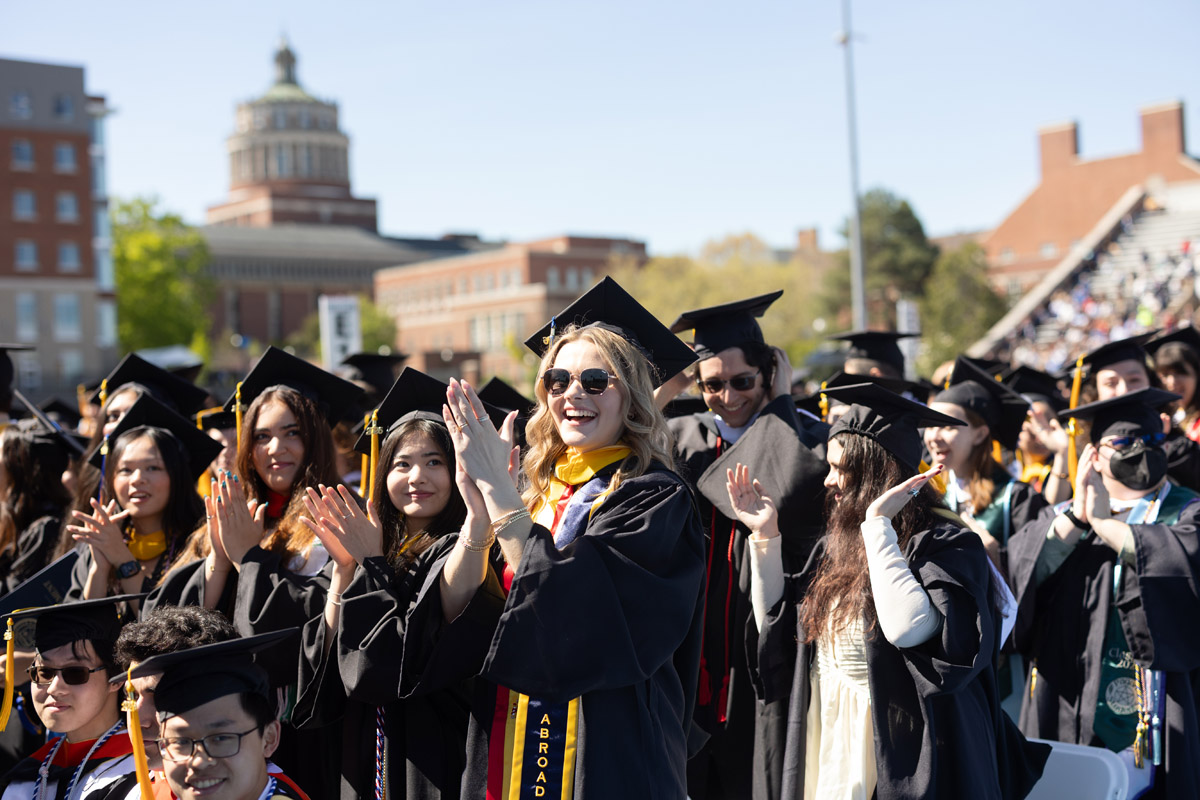 University of Rochester graduates in caps and gowns applaud during Commencement Weekend.