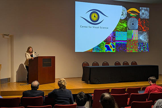 Susana Marcos speaks at a lectern in an auditorium at the Memorial Art Gallery.