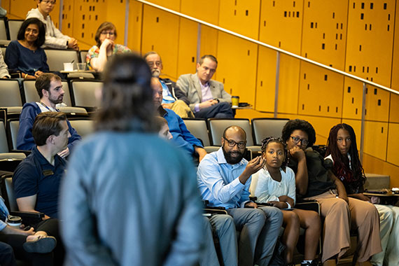 Christopher Stewart, seated in the front row of the auditorium in Wegmans Hall, asks Amanda Stent a question.