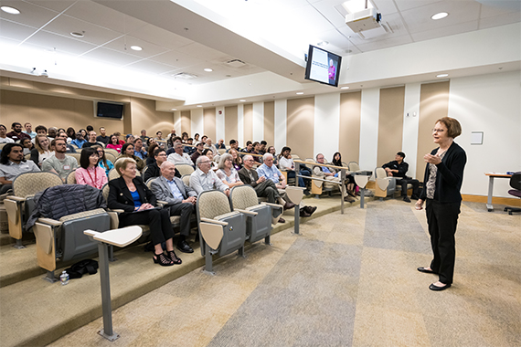 Tammy Wyant speaks in front of a packed audience at an auditorium in Goergen Hall