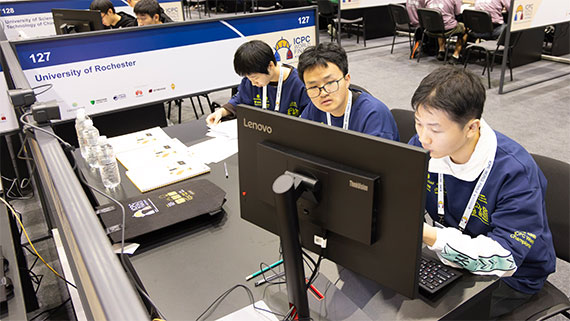 Three computer science students solve problems on a computer at a programming competition.