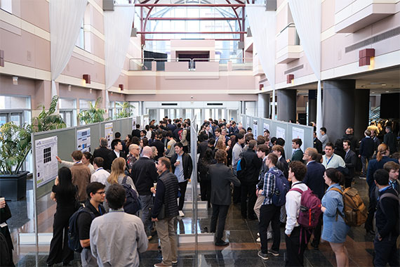 A poster session in a brightly lit atrium during the Institute of Optics Industrial Associates meeting.