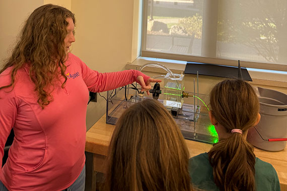A University of Rochester student demonstrates an optics experiment to elementary school students.