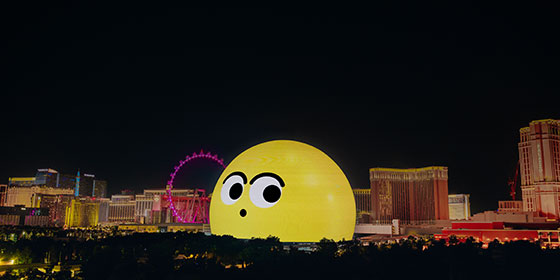 A view of the Las Vegas skyline centered on Sphere, lit up with a yellow imoji face of surprise.