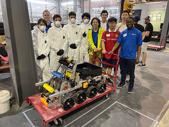 Nine students and their advisor stand behind a robot they developed for the Lunabotics competition in Florida.