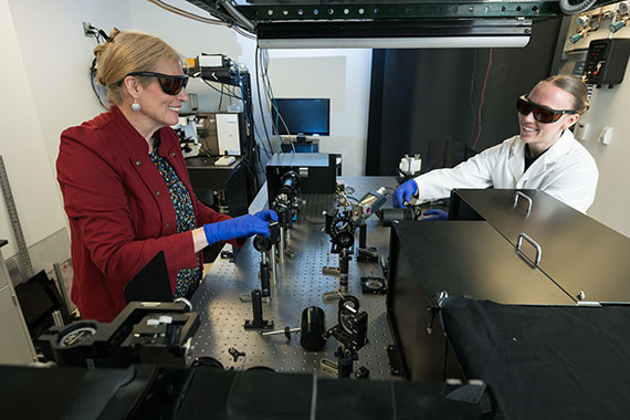 Assistant Professor Astrid Muller and her student adjust mirrors on an optical bench.