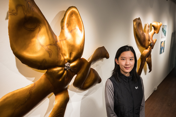 Renee Yu Jin is pictured with her sculptures in an art gallery. 