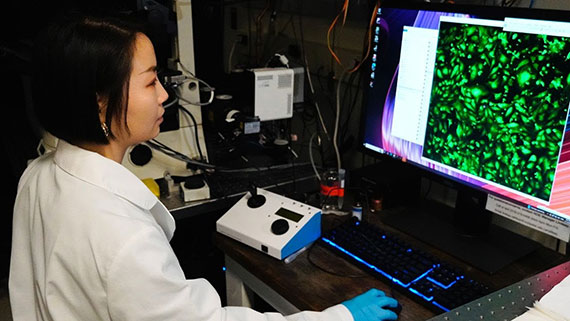 Chloe Chen looks at a computer screen with neon green dots on the display.