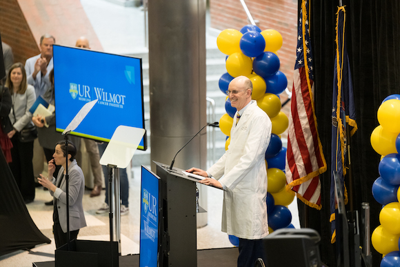 Director of the Wilmot Cancer Institute Jonathan Friedberg stands on a dais, making remarks. 