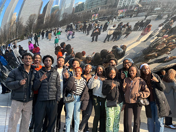 A group of 15 students from Rochester's chapter of NSBE pose in front of hte Cloud Gate sculpture in Chicago.