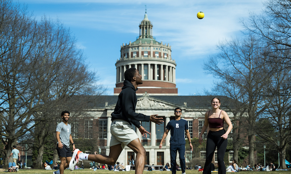 Four students play Spikeball on the quad. 