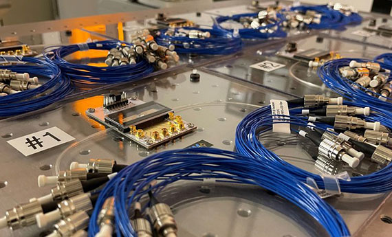 Kits filled with photonics equipment lay on an optical bench.