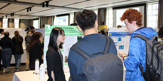 A student presents her research to onlookers in the Feldman Ballroom during the undergraduate research poster session.