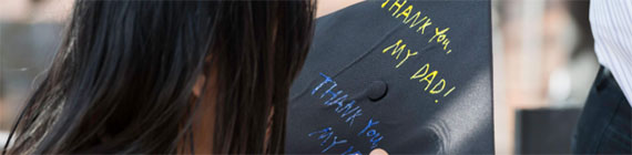 A closeup of a graduation cap with blue and yellow writing that says "Thank you my dad!"