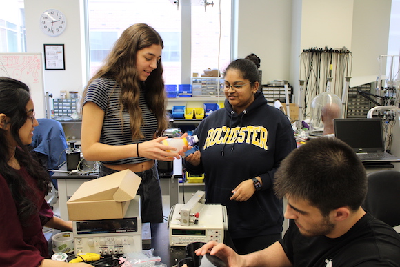 Two students hold a 3D-printed mold to create a silicone prototype of a more convenient spacer for inhalers.