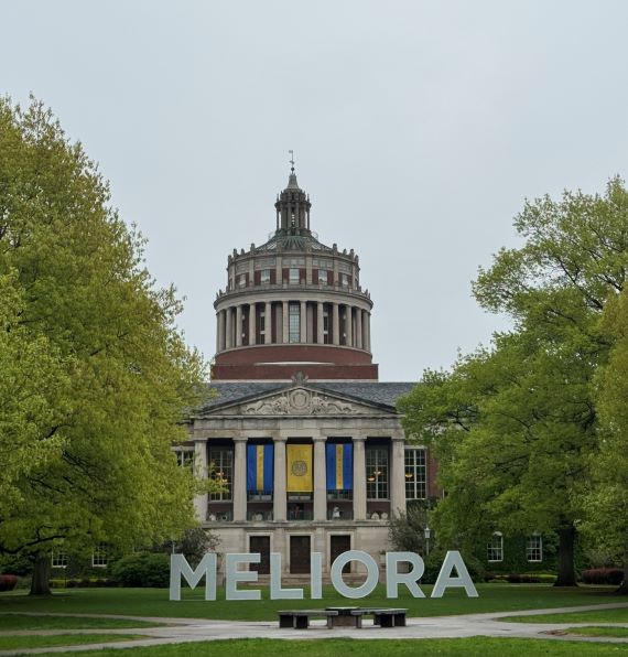 Large white letters that spell Meliora sit on the Quad outside Rush Rhees Library.