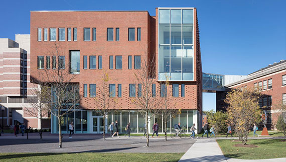 Students walk to class outside Wegmans Hall on a sunny day.