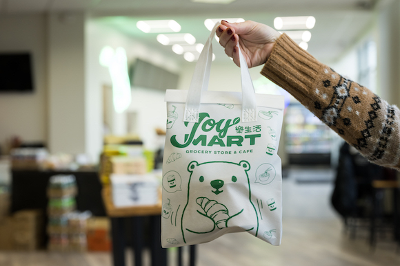 A JoyMart shopping bag being held aloft. 