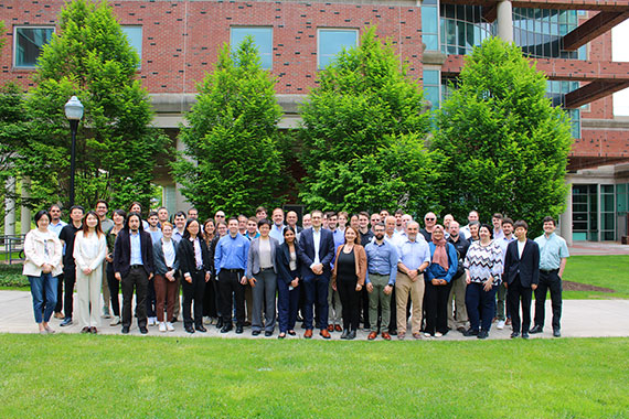 A crowd of dozens of attendees of the Center for Freeform Optics Industrial Advisory Board meeting gather outside Goergen Hall.