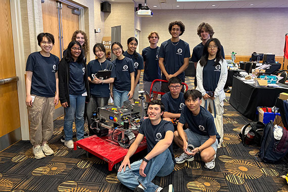 Students from the University of Rochester's Lunabotics team pose with their robot at a national competition.