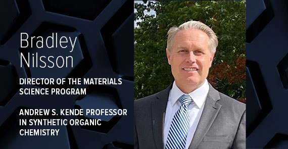 A graphic with dark blue hexagons, a headshot, and text that says "Bradley Nilsson, Director of the Materials Science Program, Andrew S Kende Professor in Synthetic Organic Chemistry."