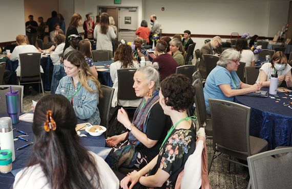 Community members are seated at several tables, getting to know one another during the CCE Engagement Summit.