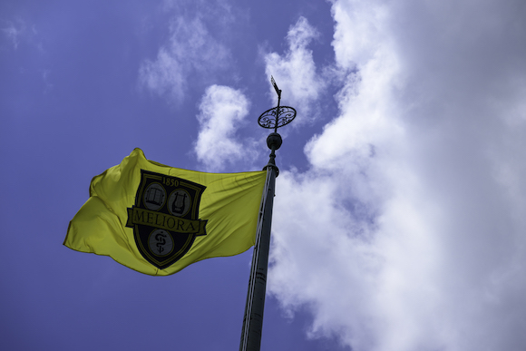 Clouds roll past the Meliora flag on University of Rochester’s Eastman Quad.
