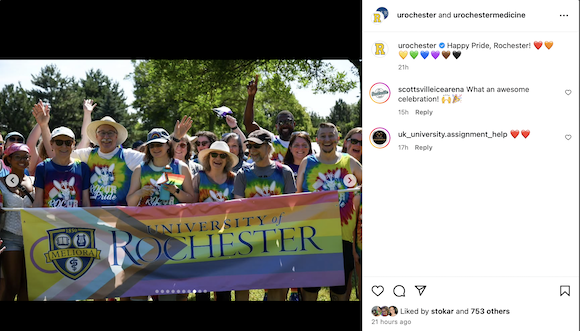 Members of the University of Rochester community marching in the Rochester Pride Parade. Participants wear tie-dyed shirts and carry a rainbow University of Rochester banner. 