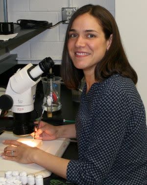 Image of Amanda Larracuente seated near a microscope.