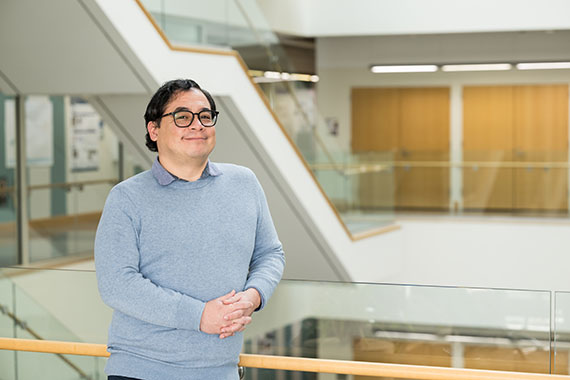 A medium shot of Ben Castañeda standing on a balcony in Goergen Hall.