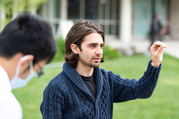A medium shot of Marc Porosoff gesturing with his left hand to explain a concept while teaching a class on the Hajim Quadrangle.