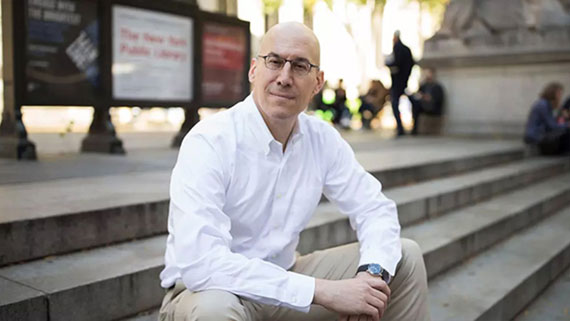 A portrait of Alex Gaeta sitting on stairs outdoors.
