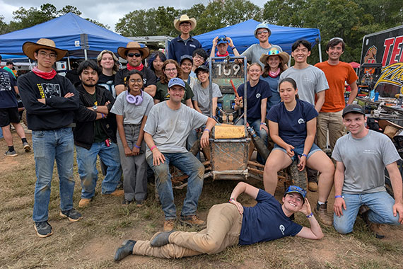 Nearly 20 students pose with their Baja SAE car at a competition in South Carolina.