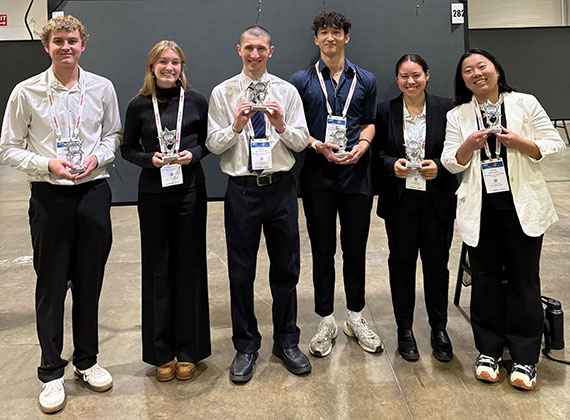 Six chemical engineering students pose with awards at the AIChE Annual Meeting.