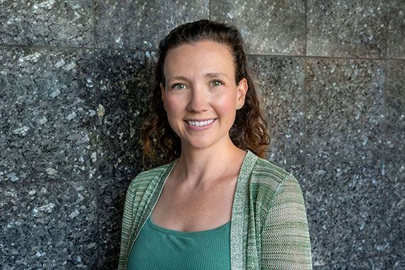 A closeup of Danae Polsin standing in front of a blackboard with equations on it.
