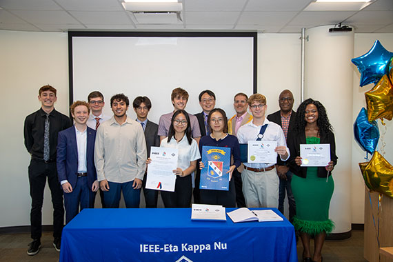 A group of students hold up certificates at the IEEE Eta Kappa Nu induction ceremony.