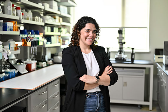 Marisol Herrera Perez standing with her arms folded next to a shelf of lab equipment.