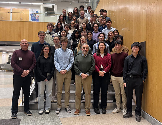 A group of dozens of students inducted into the Tau Beta Pi honor society pose on the steps of the Goergen Hall atrium.