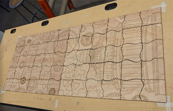 A photo of a large 60-piece jigsaw puzzle made of balsam wood on a workbench.