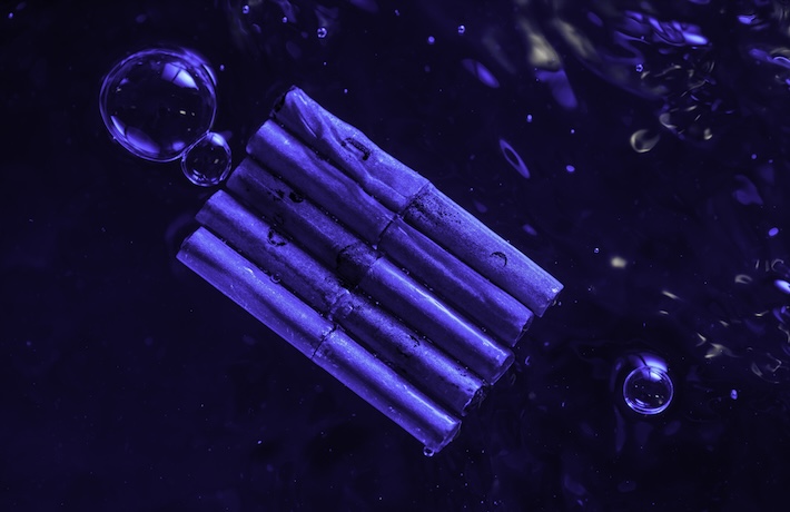 A raft of five metal tubes lit by blue light in water. 