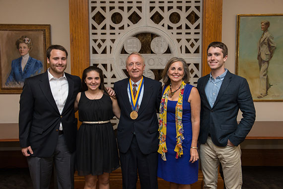 A photo of Kevin Parker wearing a medal while surrounded by his wife and three children.