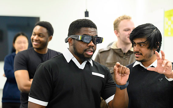 Students test Snap Spectacles in a classroom, with one gesturing while others watch and discuss the experience.