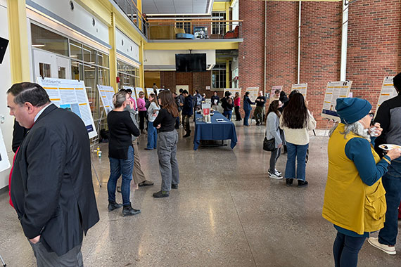 A crowd of faculty, students, and staff at a poster session in Rettner Hall.