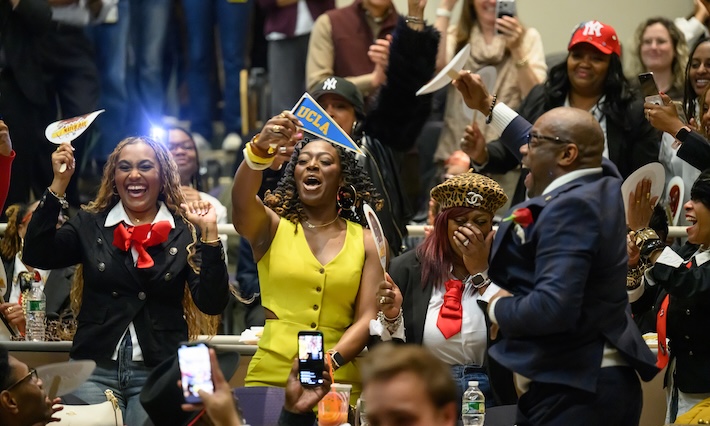 Medical student happily waves UCLA flag in a crowded auditorium. 